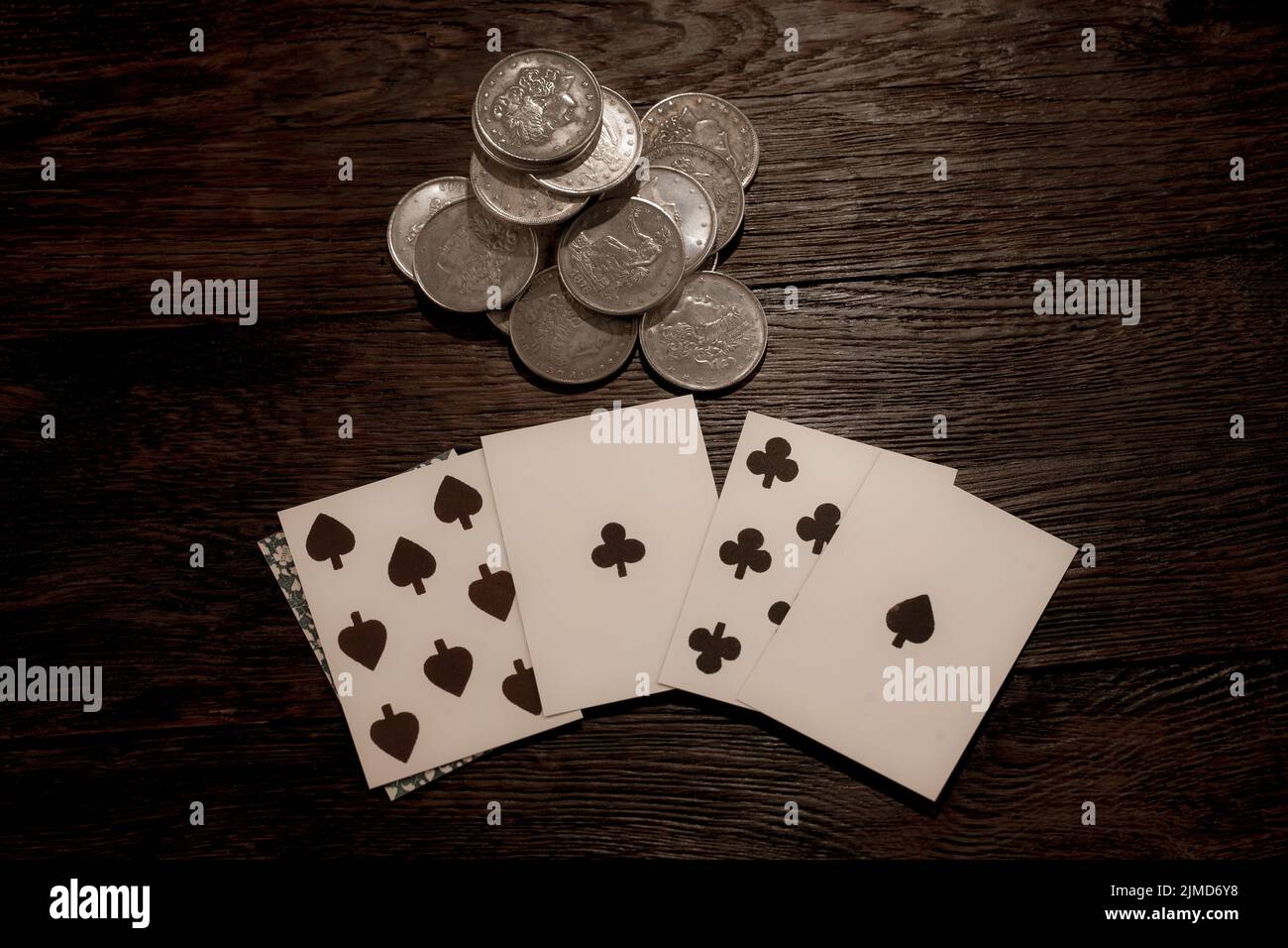 Wild west gambling. Dead man's hand and silver coins bet. Two-pair poker hand consisting of the black aces and black eights, held by Old West folk her Stock Photo