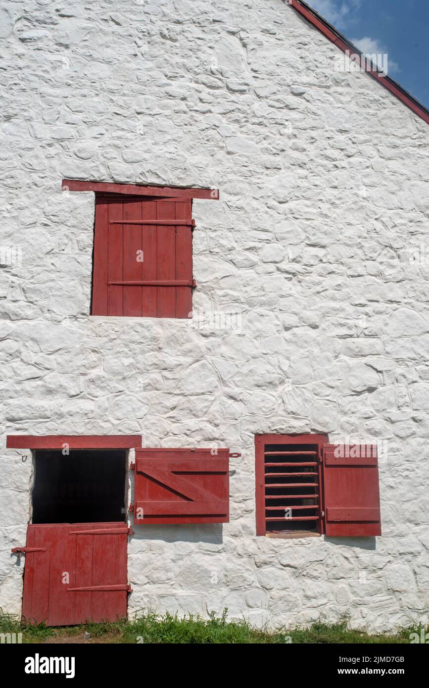 Whitewashed Pennsylvania stone barn with red split door and windows Stock Photo