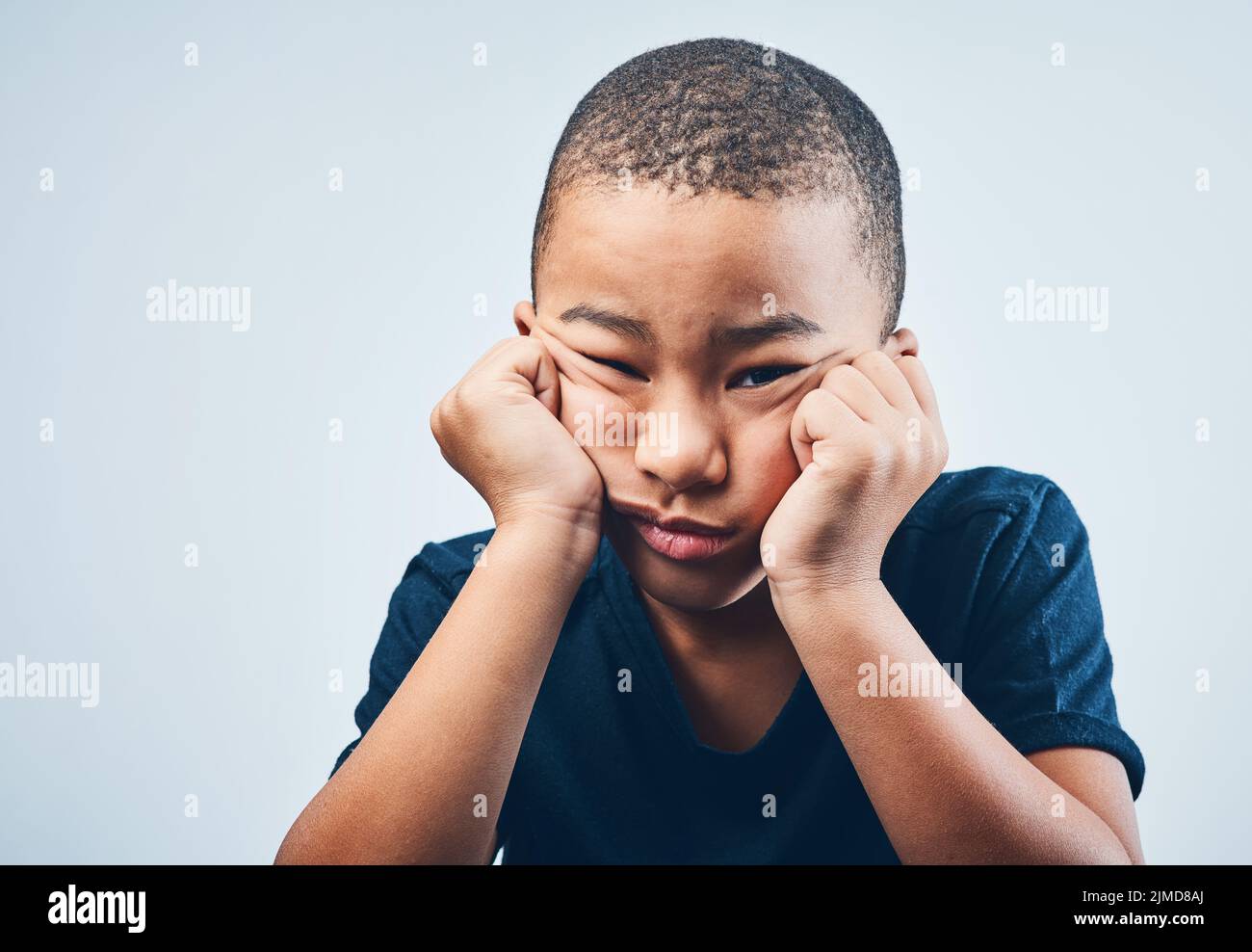 So bored even my bored is bored. Studio shot of a cute little boy looking bored against a grey background. Stock Photo