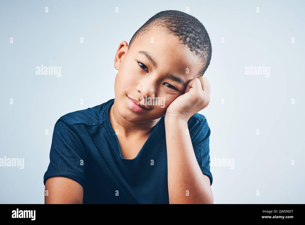Somebody entertain me... Studio shot of a cute little boy looking bored against a grey background. Stock Photo