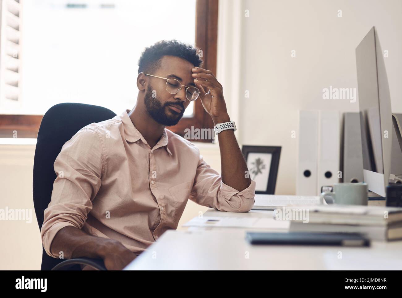 Every business has obstacles to overcome. a young businessman looking tired while working in an office. Stock Photo