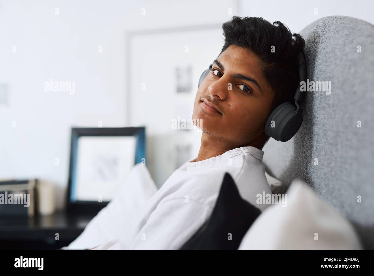 My choice of music is based on my mood. a young man listening to music through his headphones while relaxing at home. Stock Photo