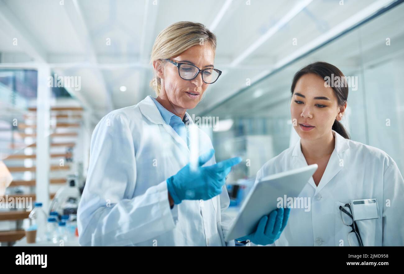 Using multiple resources to test new methods. two scientists working together on a digital tablet in a lab. Stock Photo