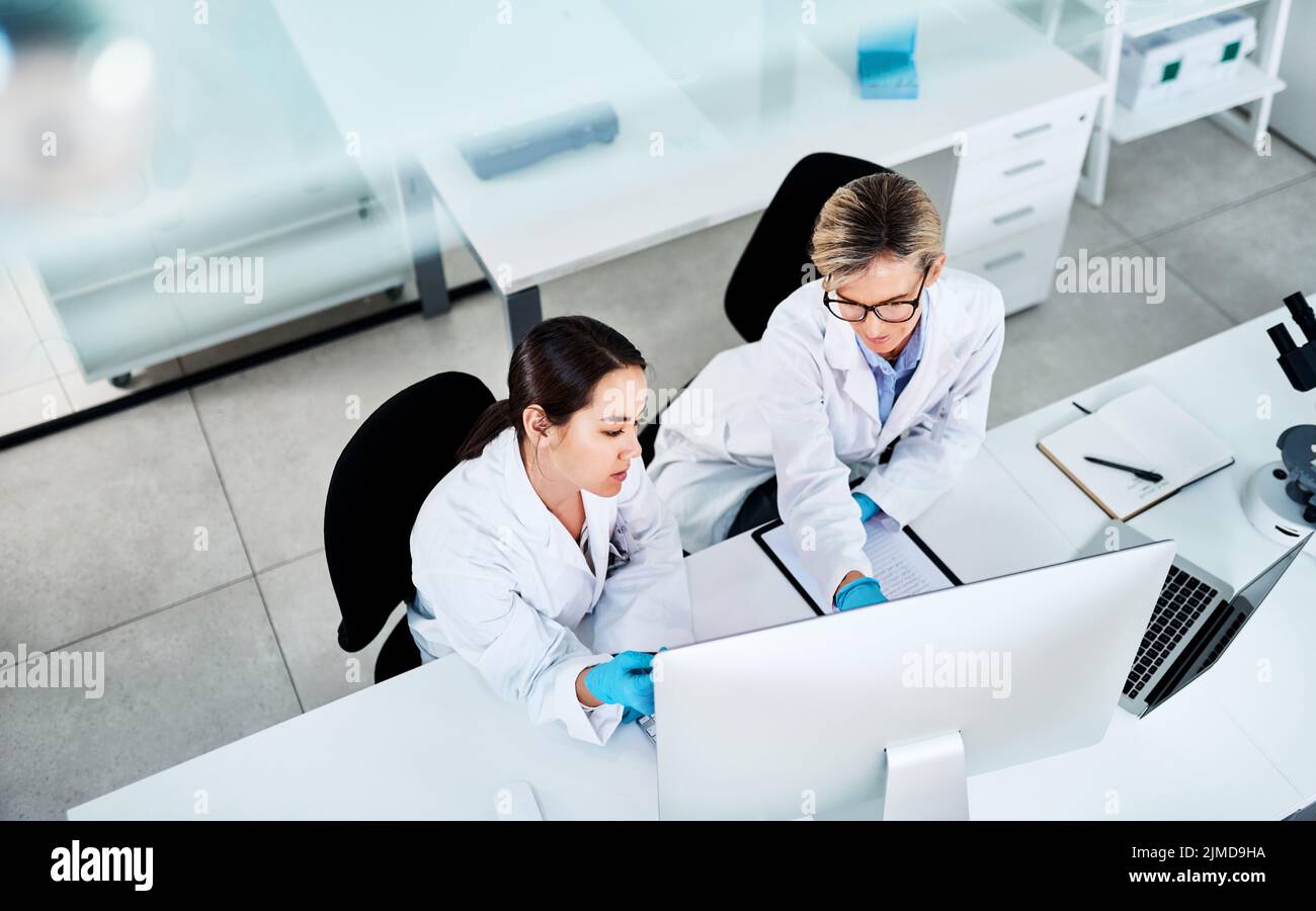 Putting their heads together on a new mystery. two scientists working together on a computer in a lab. Stock Photo