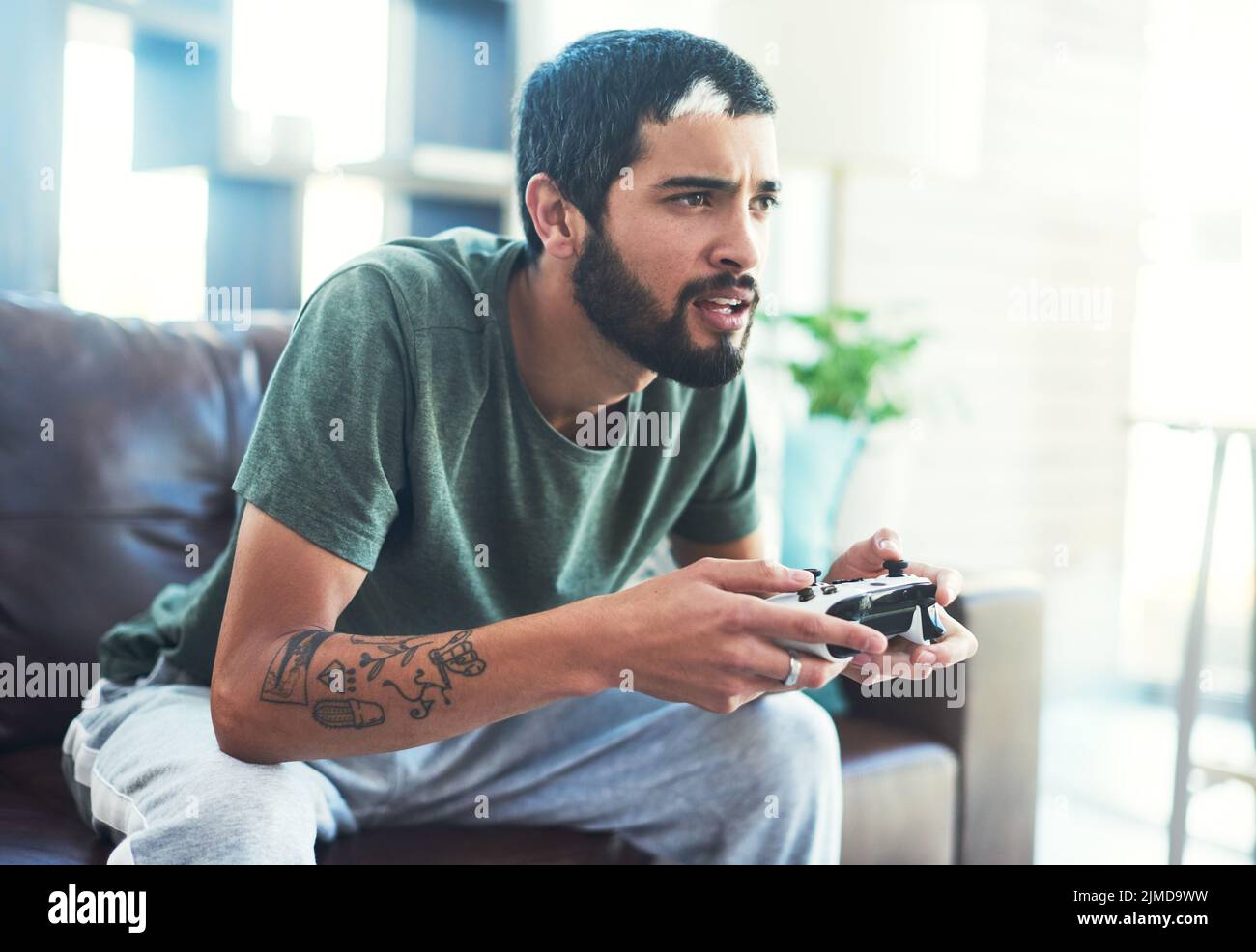Playing video games is a great way to destress. a young man sitting on the couch while playing