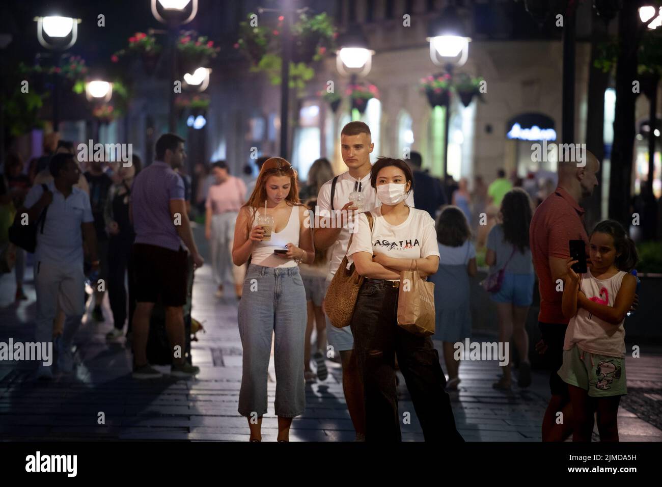 Picture of a young asian people walking in the streets of Belgrade, Serbia, while wearing a protective face mask, during the 2020 2021coronavirus covi Stock Photo