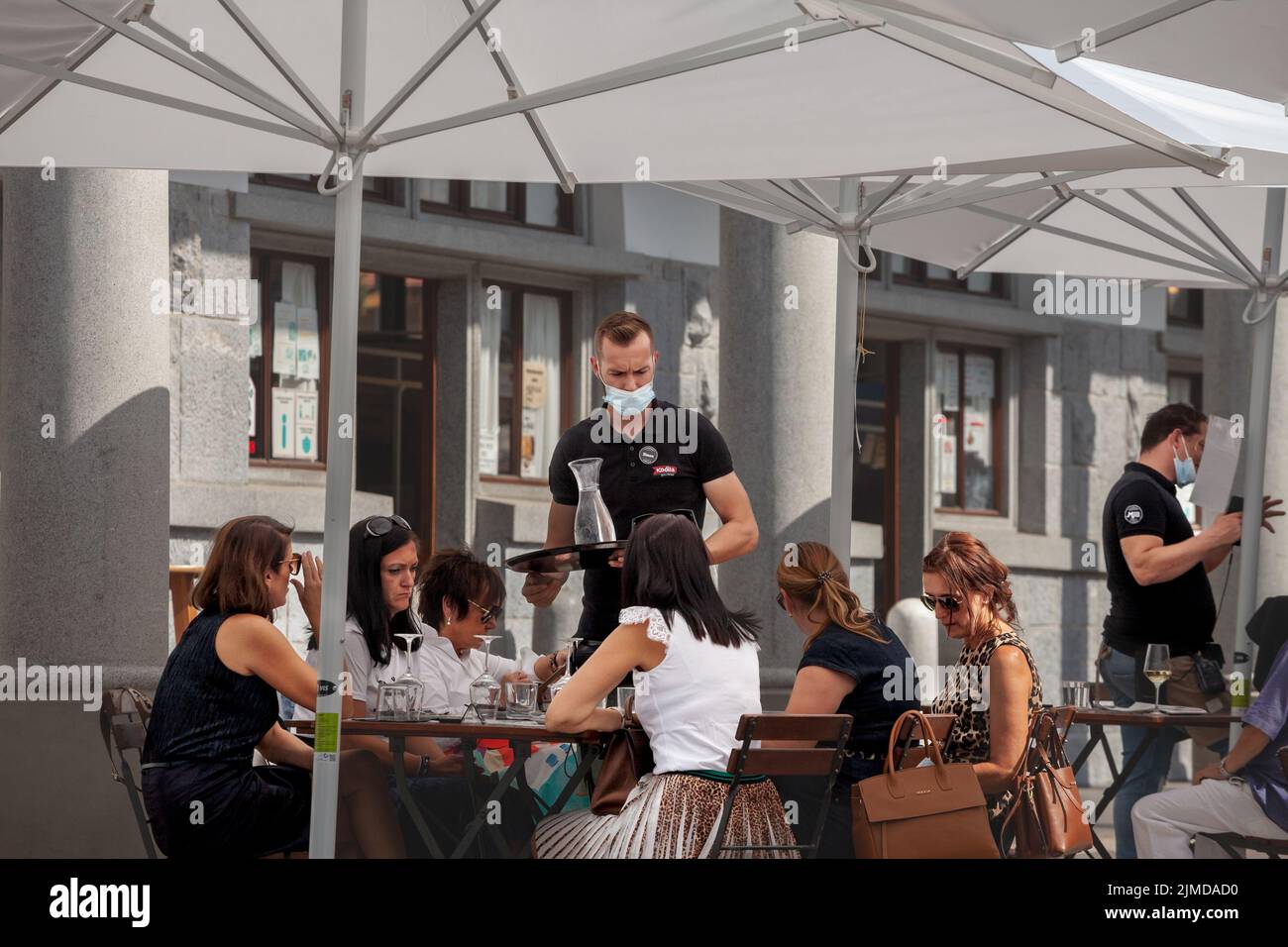 Picture of a white caucasian man, a waiter in Ljubljana, Slovenia, working and serving people while wearing a respiratory face mask during the coronav Stock Photo