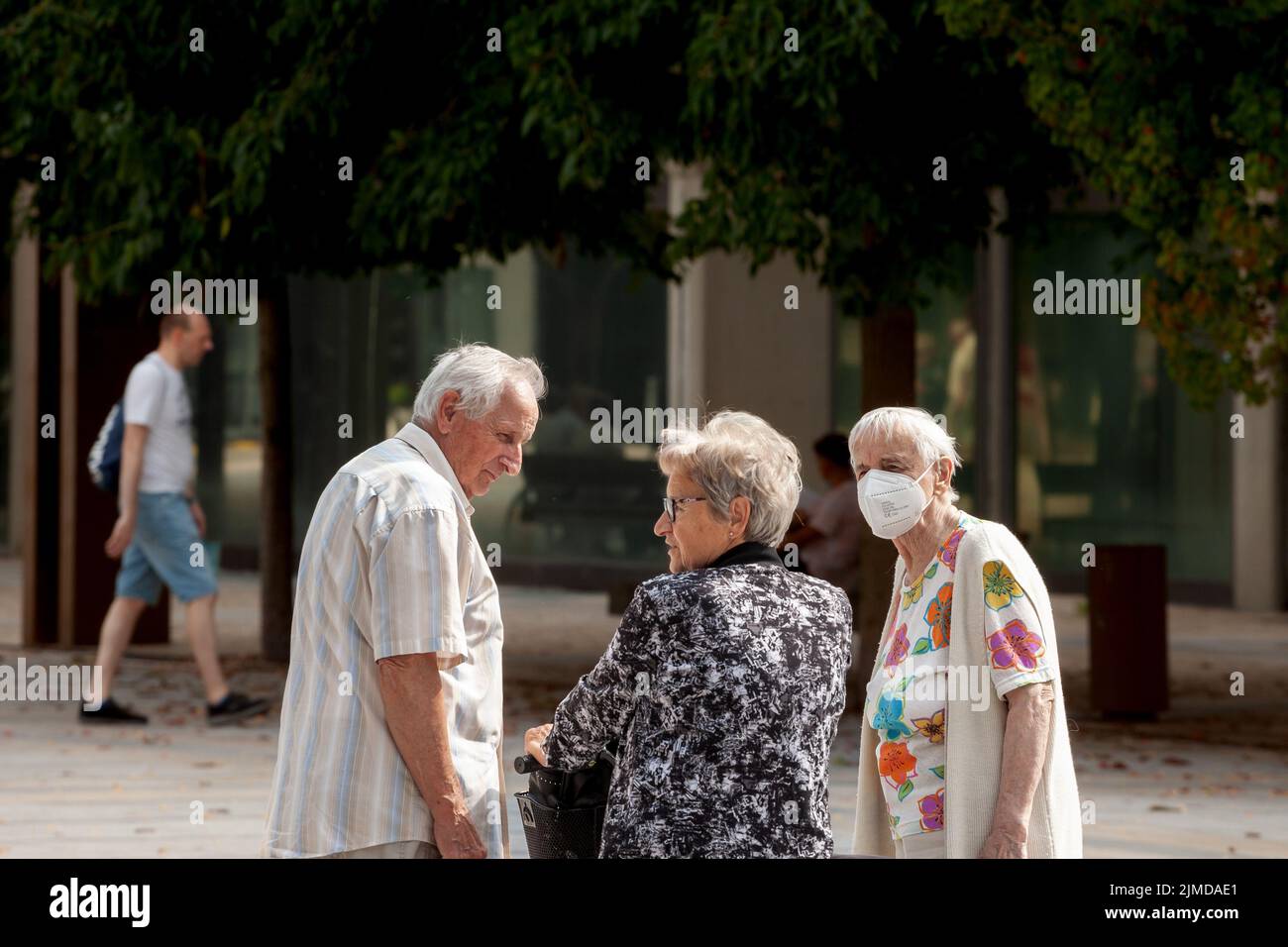 Picture of a white caucasian senior woman in Ljubljana, capital city of Slovenia socializing and discussing with older people, friends, while wearing Stock Photo