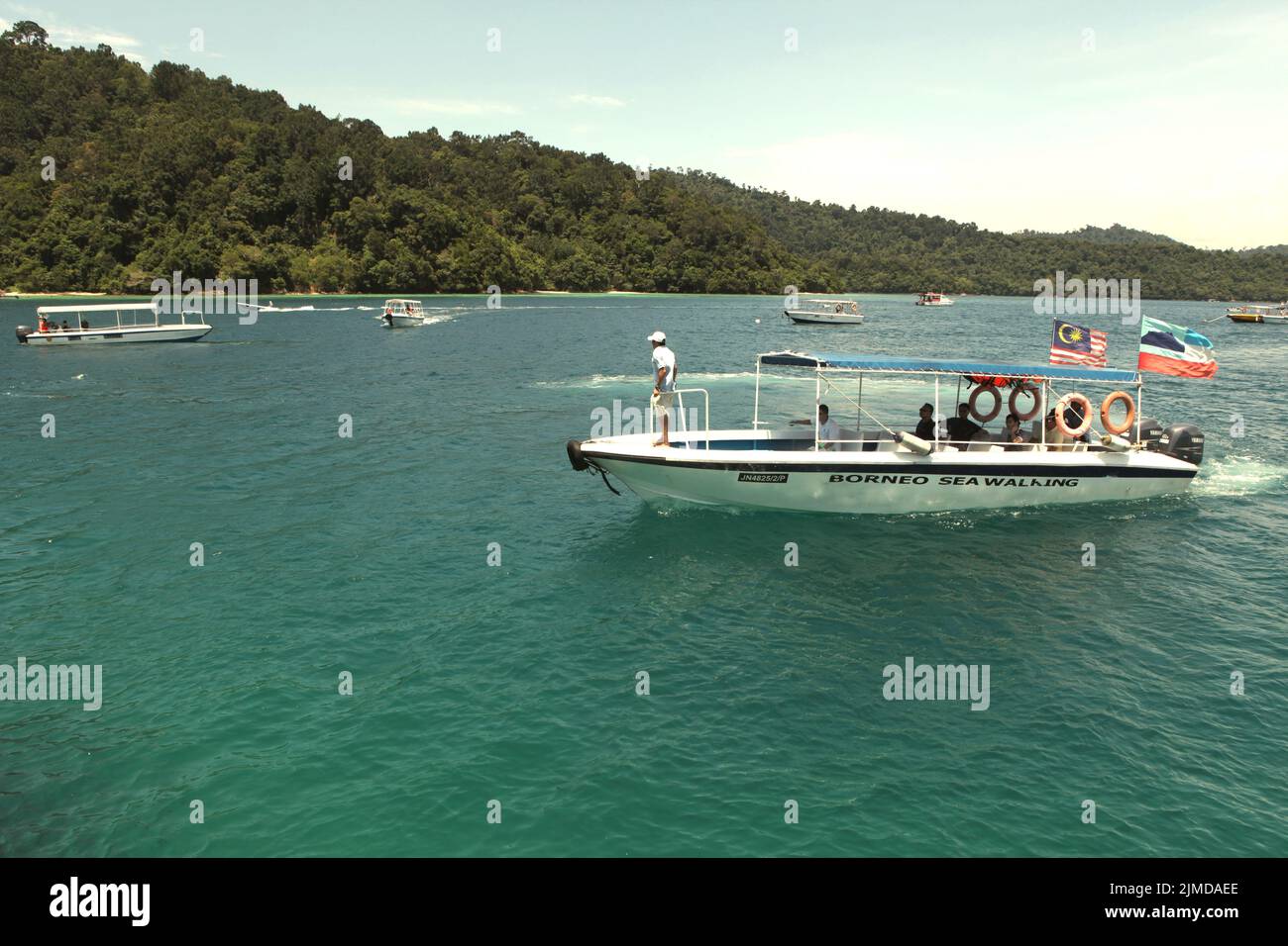 A boat carrying tourists sailing on the water within the area of Tunku Abdul Rahman Park in Sabah, Malaysia. Stock Photo