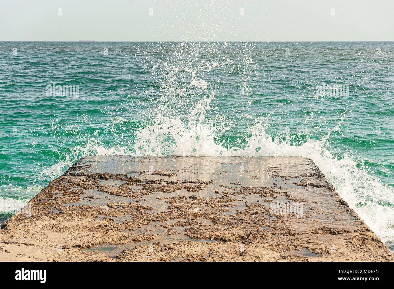 Sea â€‹â€‹waves break with splashes on the breakwater pier near the coast Stock Photo