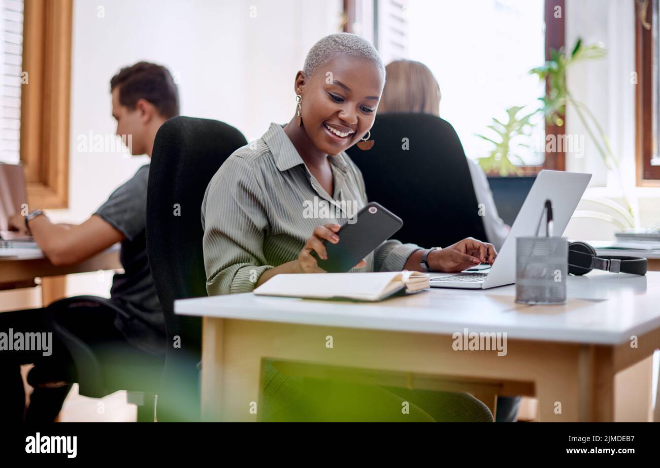 Checking her notifications. a young businesswoman using a cellphone while working in an office. Stock Photo