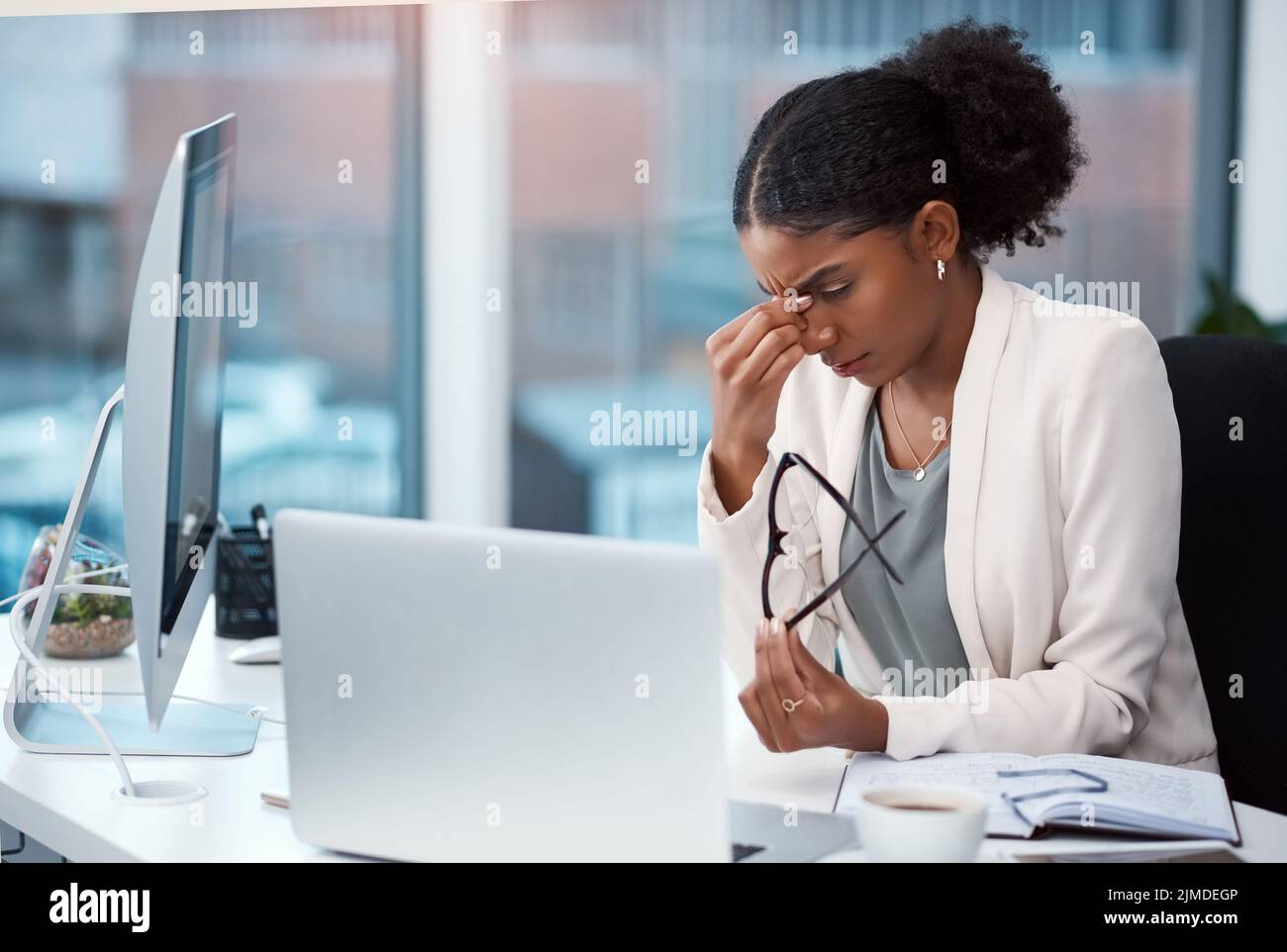 Female intern suffering from a headache or migraine due to stress caused by deadlines and work pressures. Professional in pain feeling bad, stressed Stock Photo