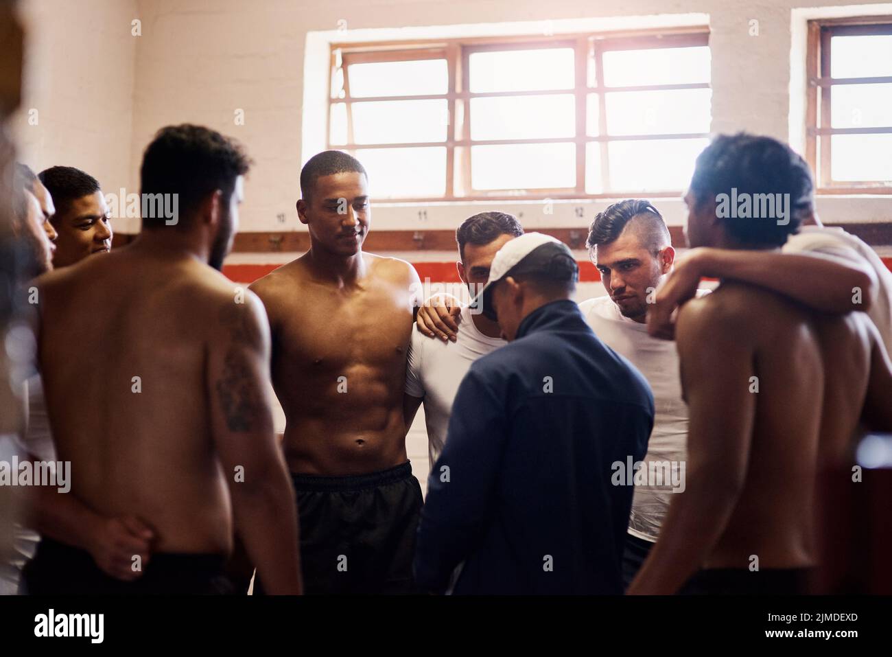 Forget sports team, theyre a family. a rugby coach addressing his team players in a locker room. Stock Photo