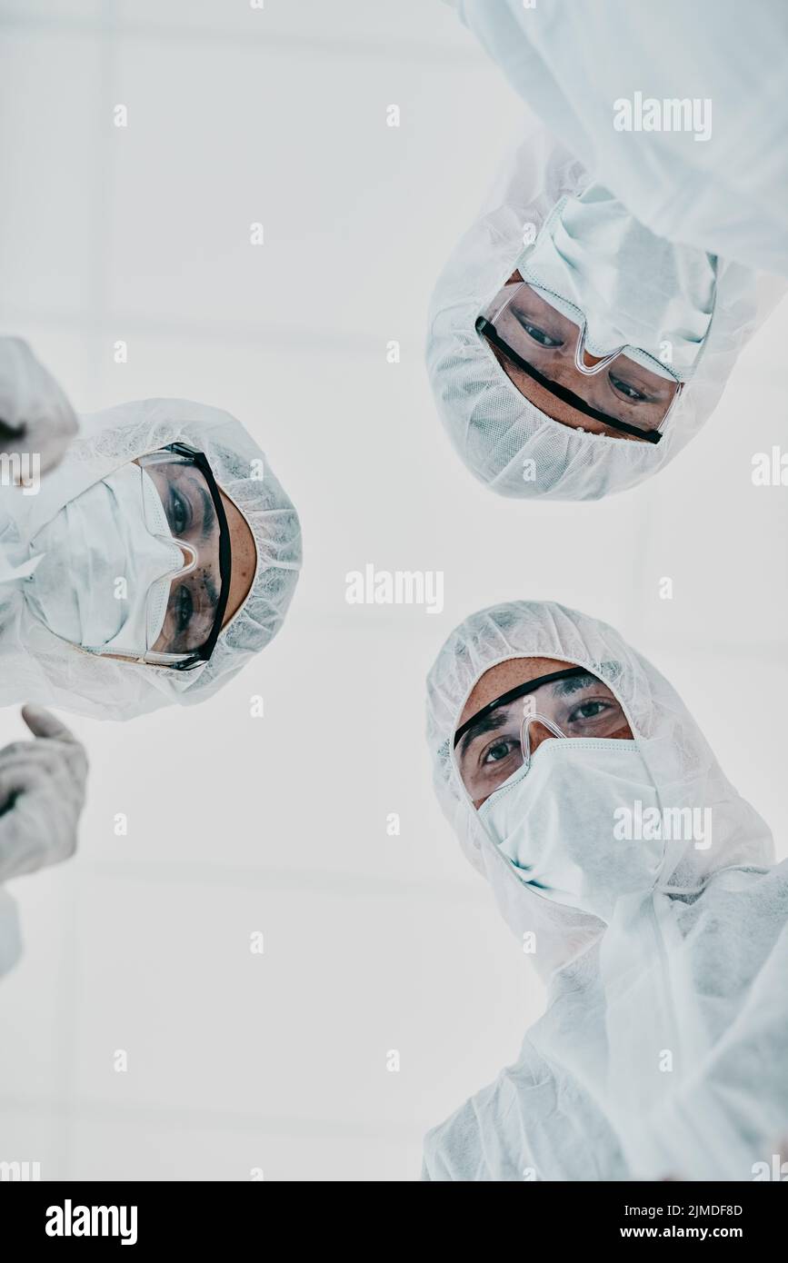 Covid, pandemic and team doctors, scientists or medical workers wearing protective ppe to prevent spread of a virus from below. Virologist group Stock Photo
