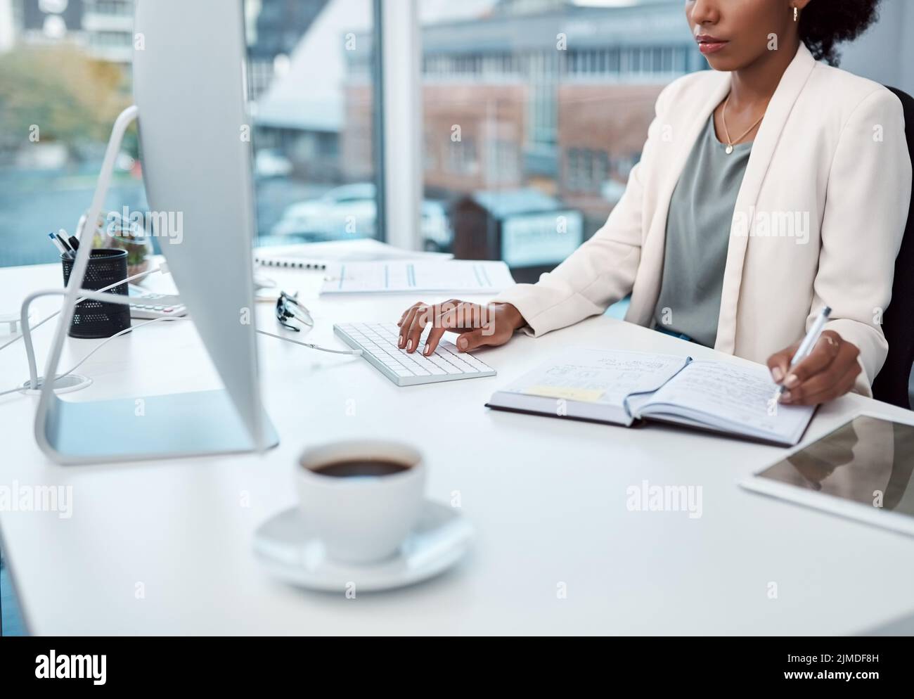 Writing notes, typing on a computer and working at her desk with a corporate and professional business woman. Manager, boss or CEO scheduling Stock Photo