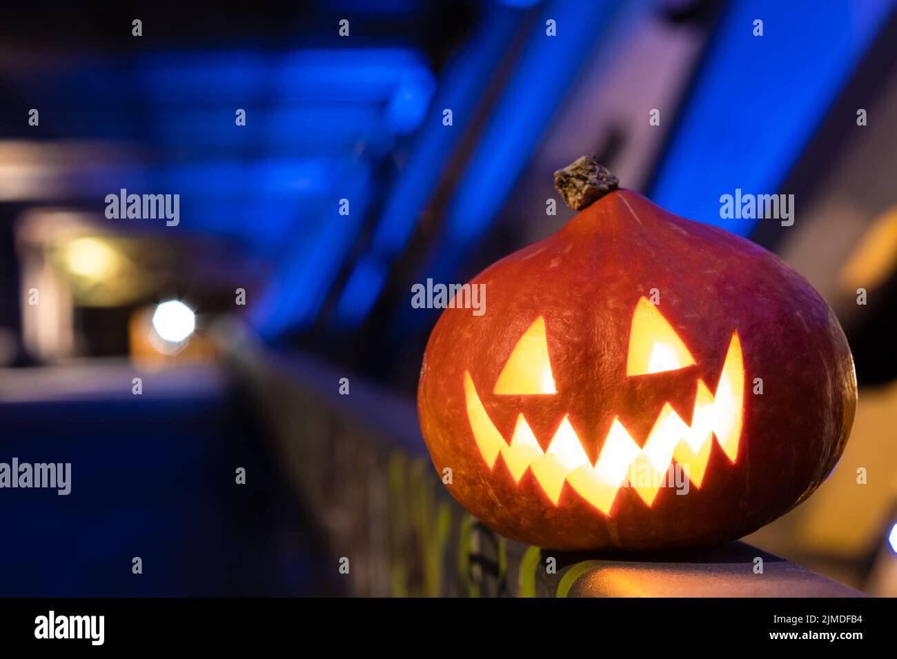 Halloween pumpkin in the dark on a blue industrial abstract background. Blurry colored lights. Stock Photo