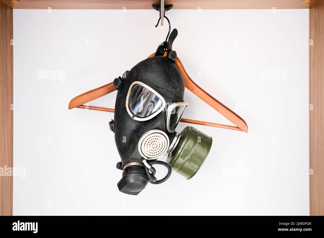 Coronavirus. A black gas mask hangs on the clothes hanger in an empty wardrobe. Stock Photo
