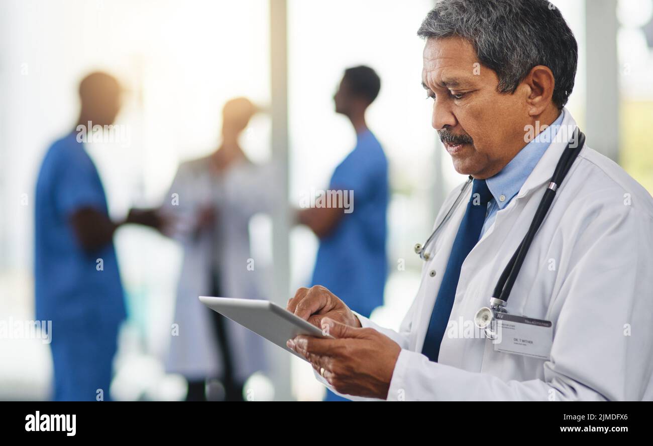 Doctor with tablet reading test results, browsing treatment options and