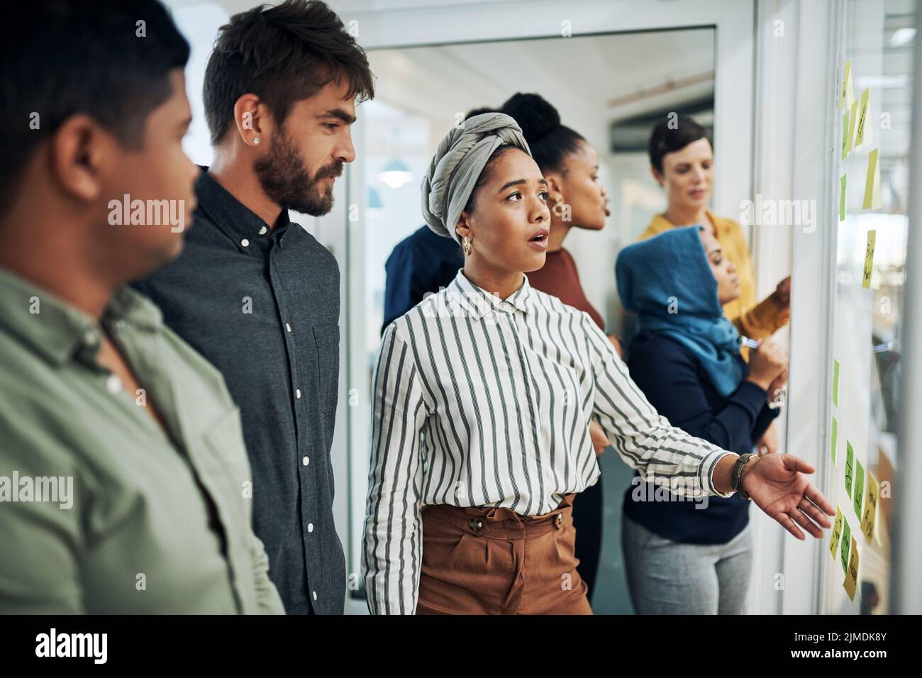 Discussing the big plans they all have. a group of businesspeople brainstorming with notes on a glass wall in an office. Stock Photo