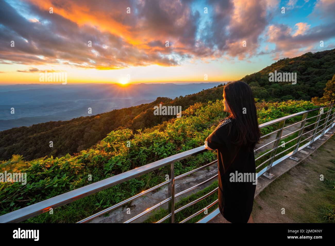 Tropical forest nature landscape view with woman toursit looking sunset mountain range at Doi Inthan Stock Photo