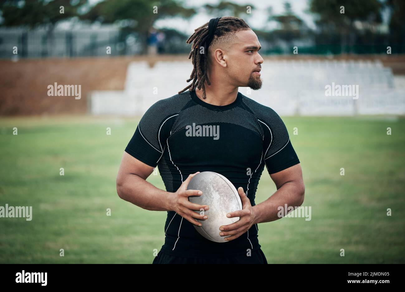 Youre looking at a future rugby cup winner. a handsome young rugby player holding a rugby ball while standing on the field. Stock Photo