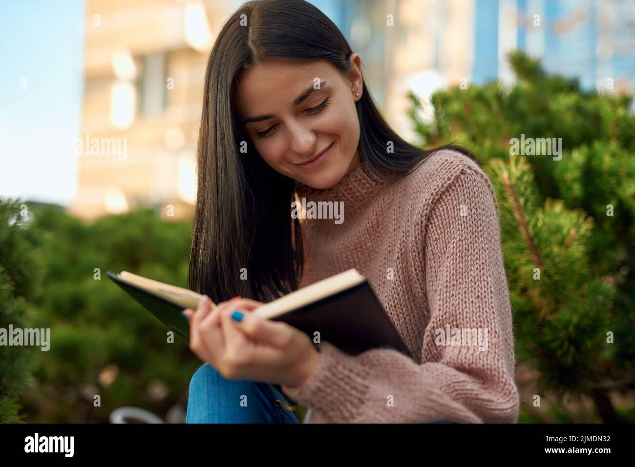 Smiling lady reading personal journal on the street Stock Photo