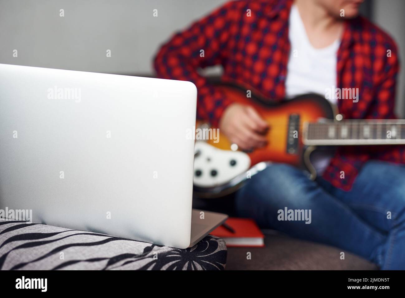 Stylish guy learning to play the guitar at home. Video communication training. Distance learning. Quarantine restrictions Stock Photo