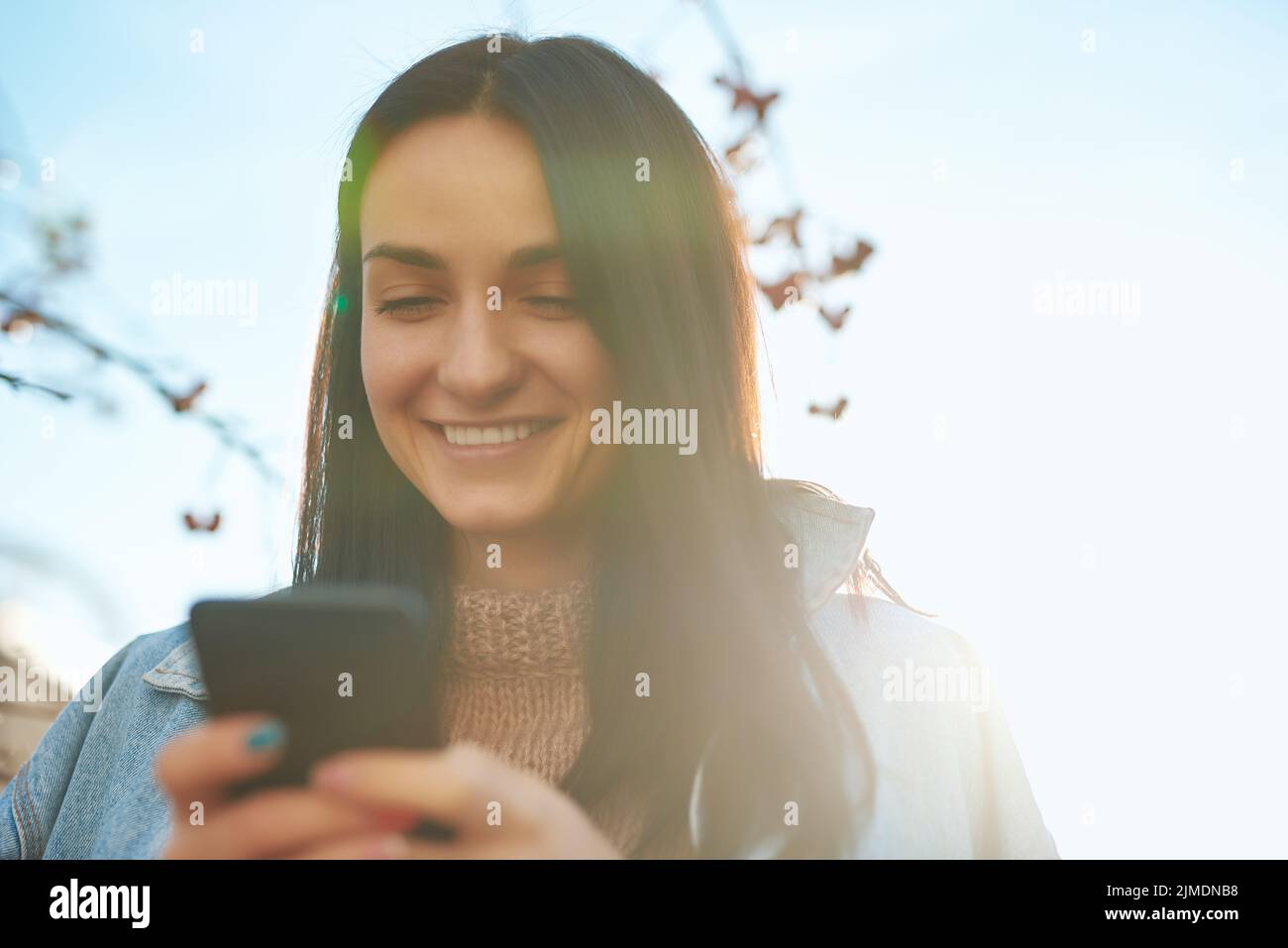 Smiling lady making call by her smartphone outdoors Stock Photo