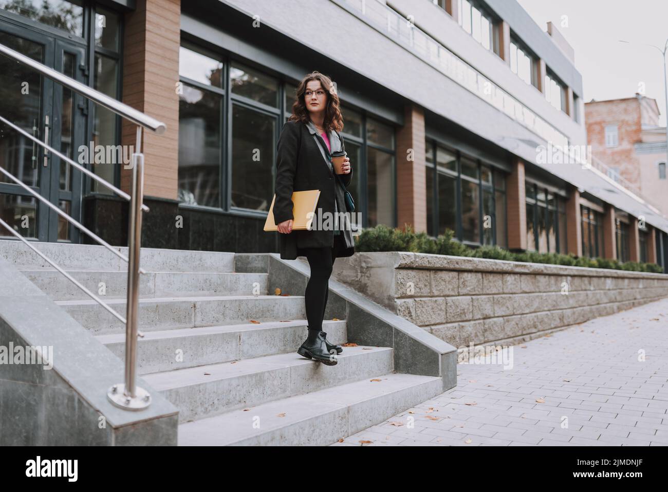 Young female walking out of the new office building Stock Photo