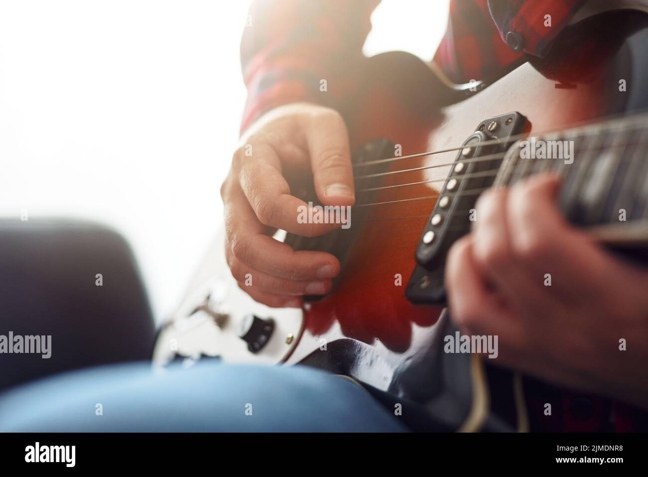 Stylish guy learning to play the guitar at home. Video communication training. Distance learning. Quarantine restrictions Stock Photo