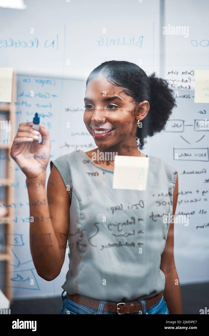 Project manager writing on a whiteboard to plan ideas and visualize business strategy. Focused, confident and thoughtful businesswoman showing Stock Photo