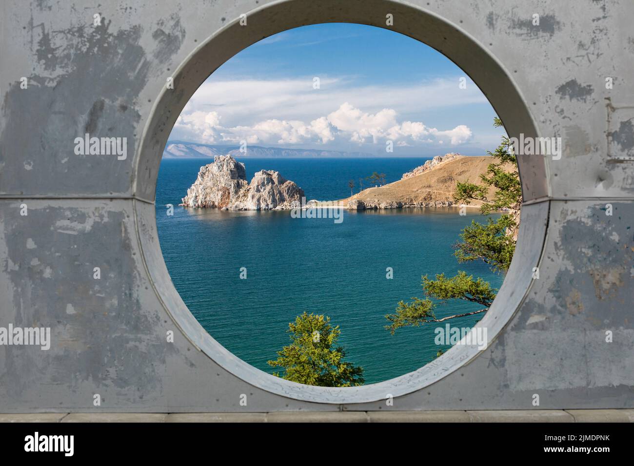 View of blue sky, sea and mountains through hole in concrete wall