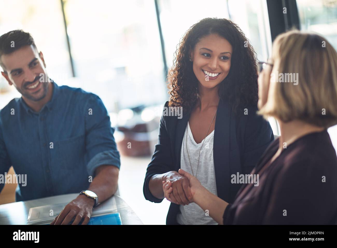 Handshake by businesswomen to congratulate in a meeting at work. Business professionals greet and make deals to collaborate in a corporate office Stock Photo