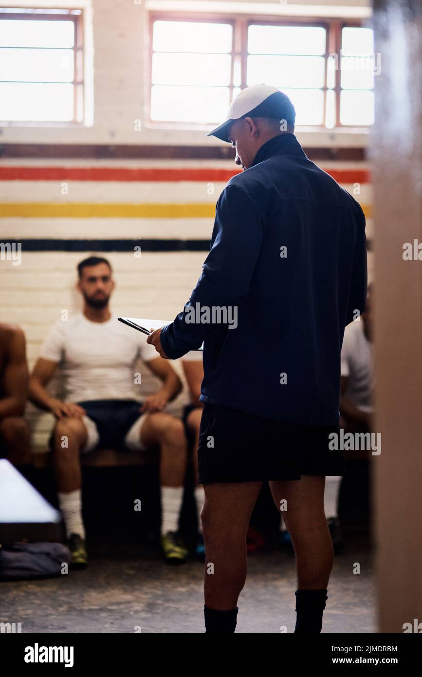 A sure win takes proper planning. a rugby coach addressing his team players in a locker room. Stock Photo
