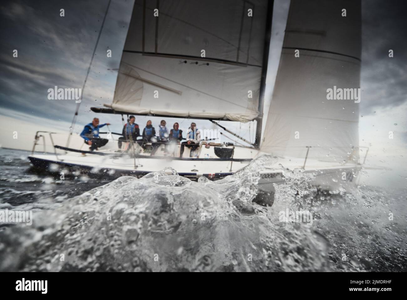 Participants of a sailing regatta on the sailboat, pull ropes, water splashes in the foreground, focus on splashes Stock Photo