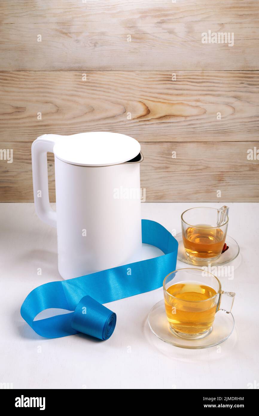 https://c8.alamy.com/comp/2JMDRHM/tea-cup-and-electric-kettle-on-white-table-at-home-in-wooden-house-2JMDRHM.jpg