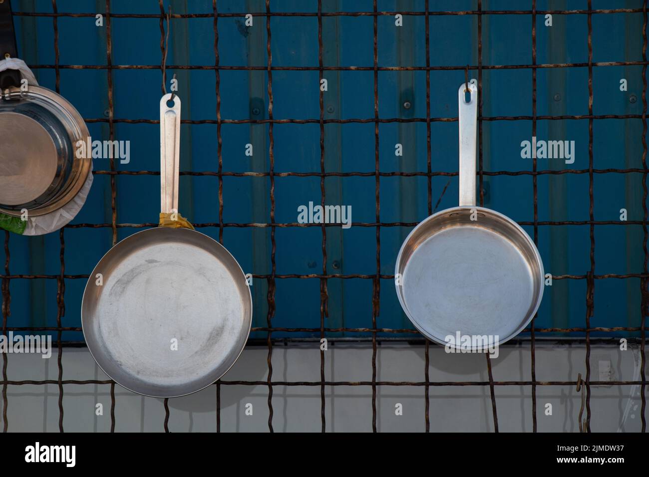 https://c8.alamy.com/comp/2JMDW37/cast-iron-pans-hang-on-grates-on-the-wall-kitchen-utensils-are-new-and-clean-2JMDW37.jpg