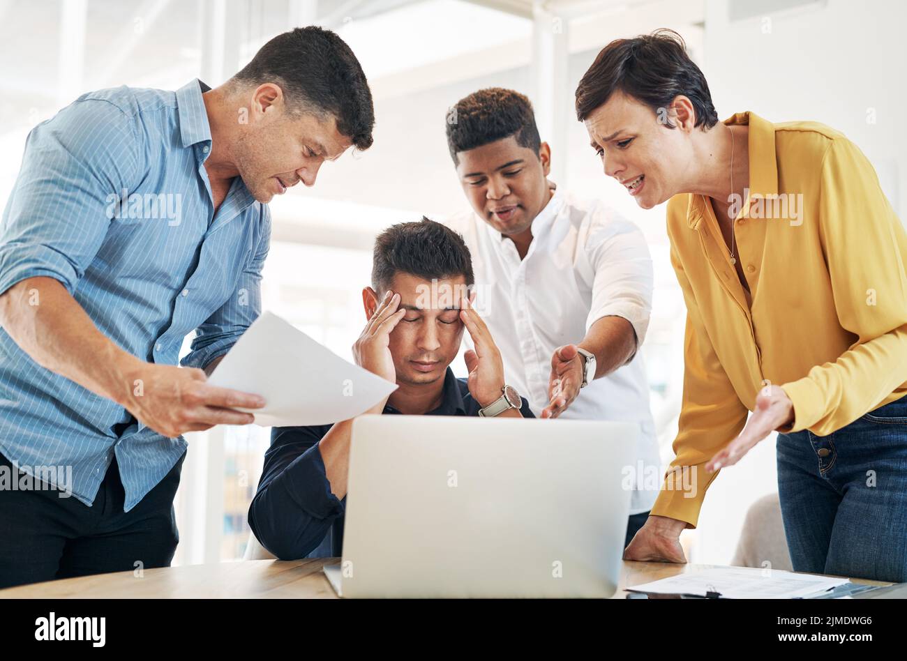 Im so done with this day. a young businessman surrounded by demanding colleagues while working at his desk in an office. Stock Photo