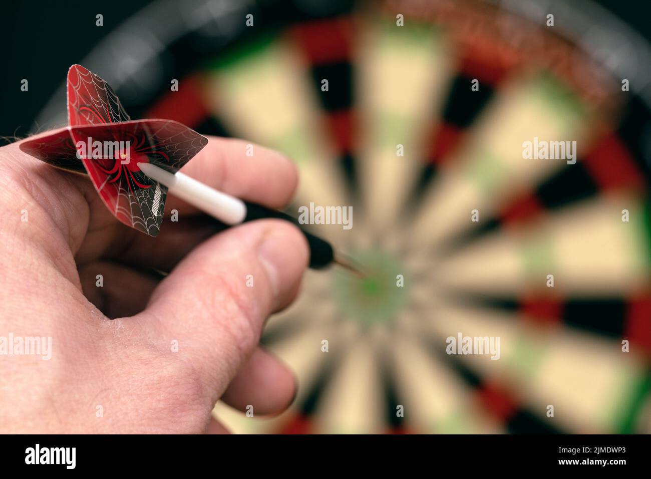 Man hand is holding dart and aiming at target. Achieving goal. game of darts. Stock Photo