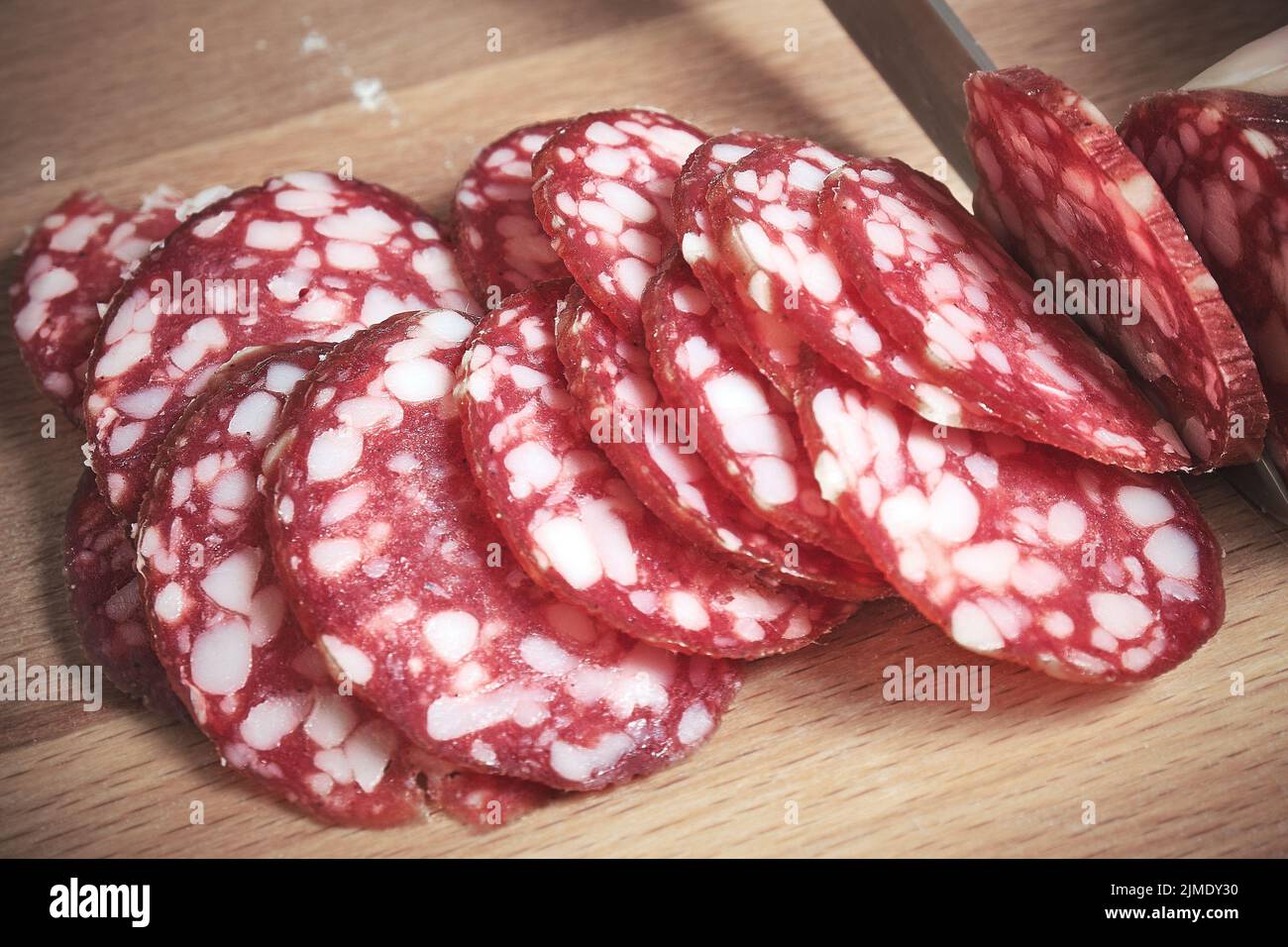 The knife cuts the smoked sausage into pieces Stock Photo Alamy