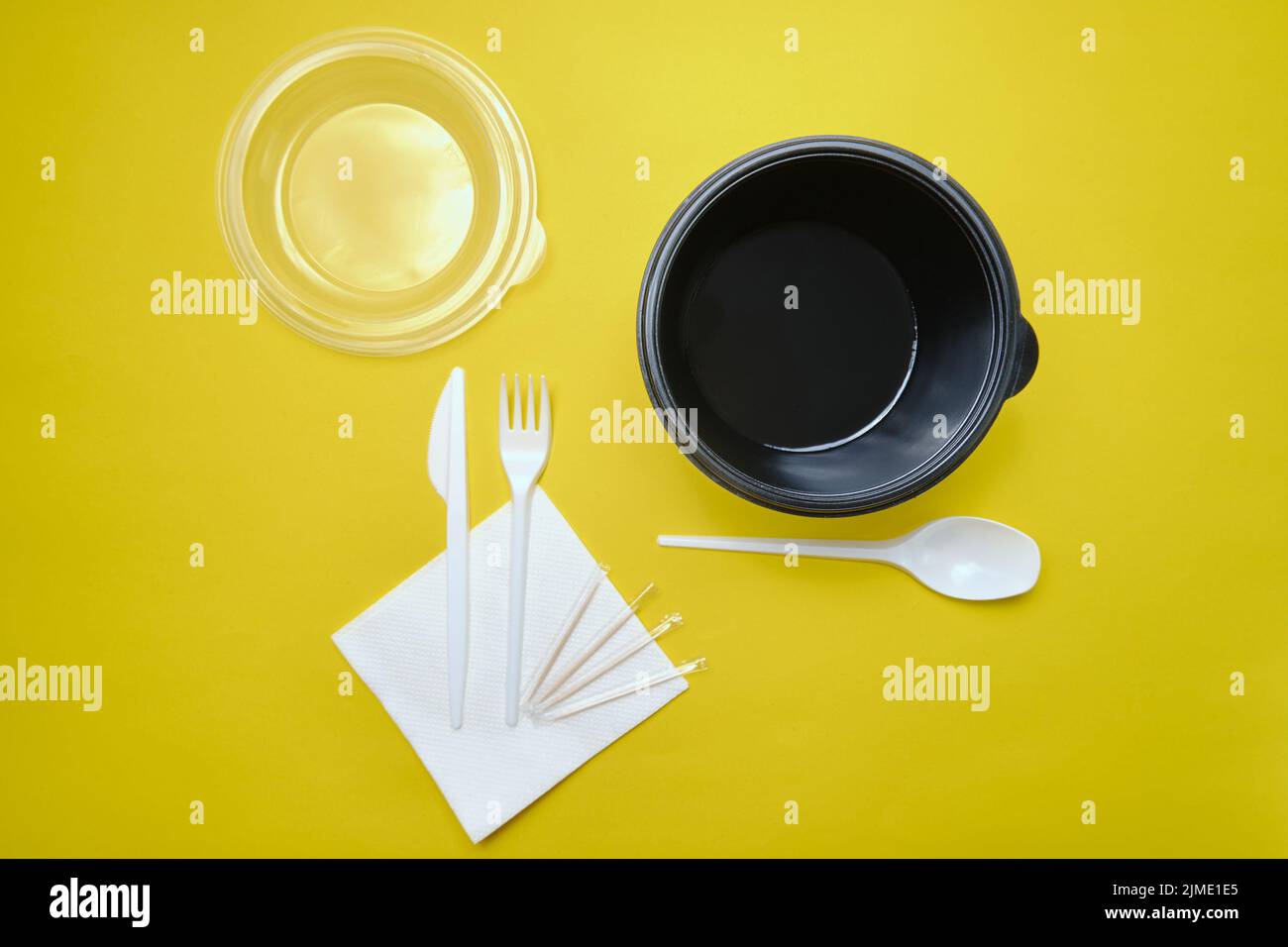Disposable plastic tableware on yellow background Stock Photo