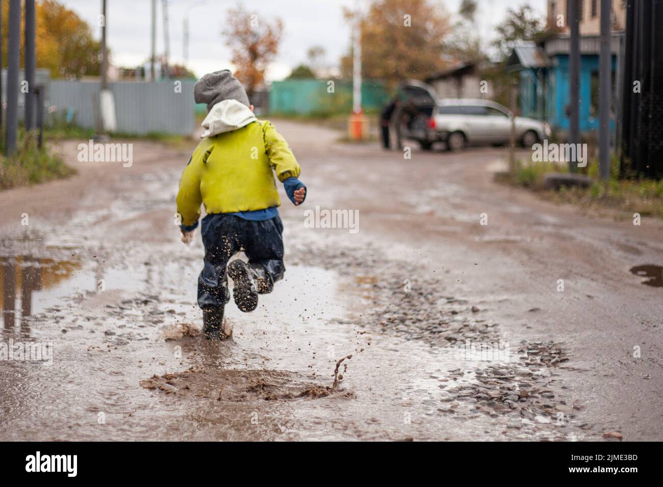 The boy runs through the puddles. Disobedient child Stock Photo
