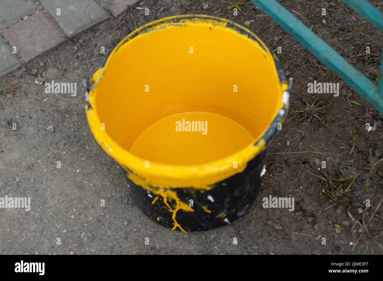 A bucket of yellow paint. Paint for painting parking posts. Stock Photo