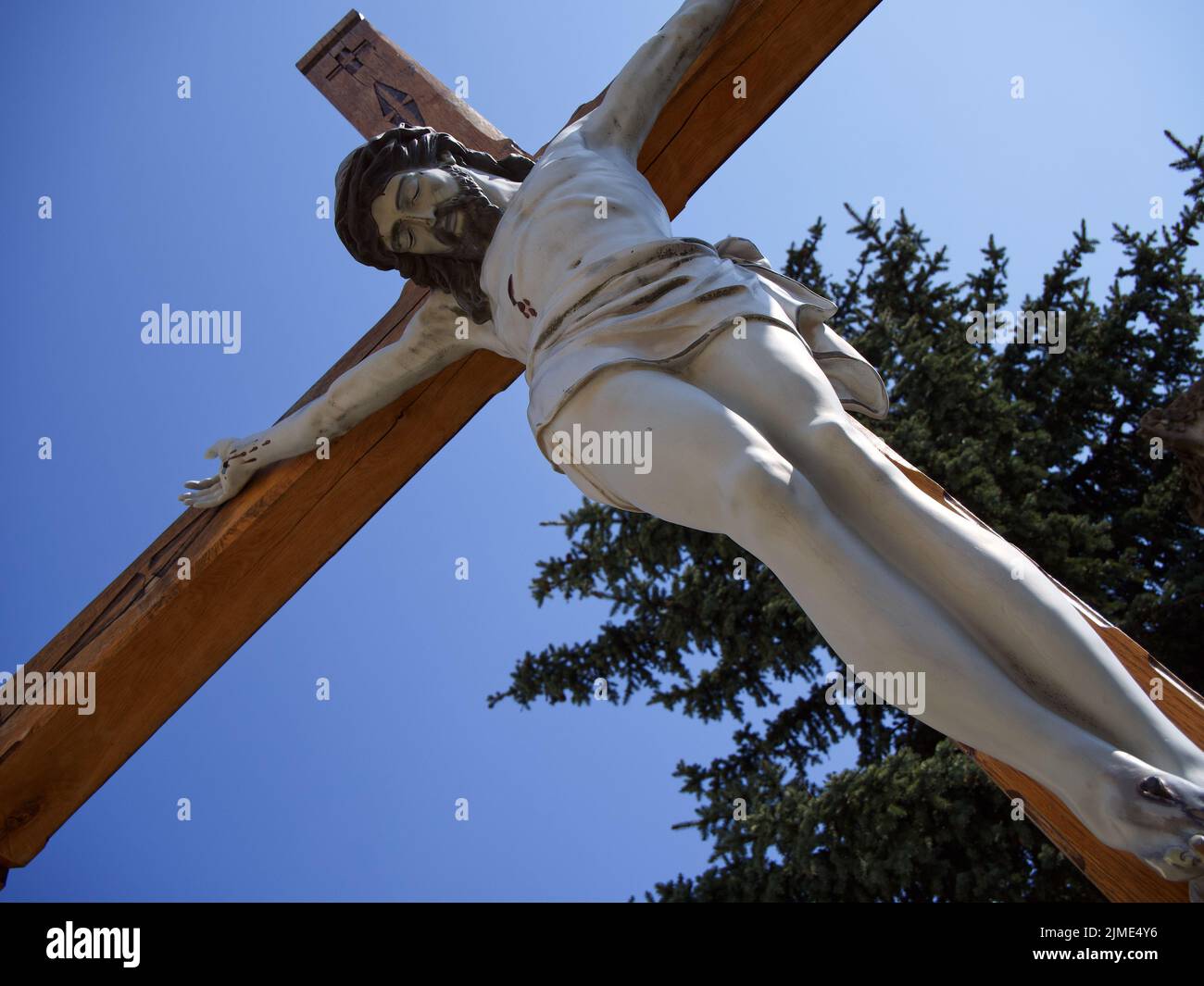 A sculptural image of the crucified Jesus Christ against a clear sky. Bottom view. Stock Photo