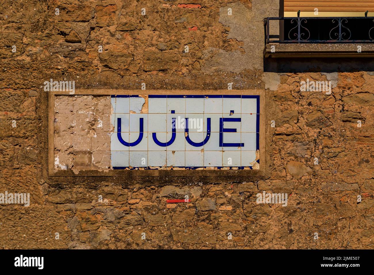 Old damaged tile sign with the village name on a stone wall in a ...