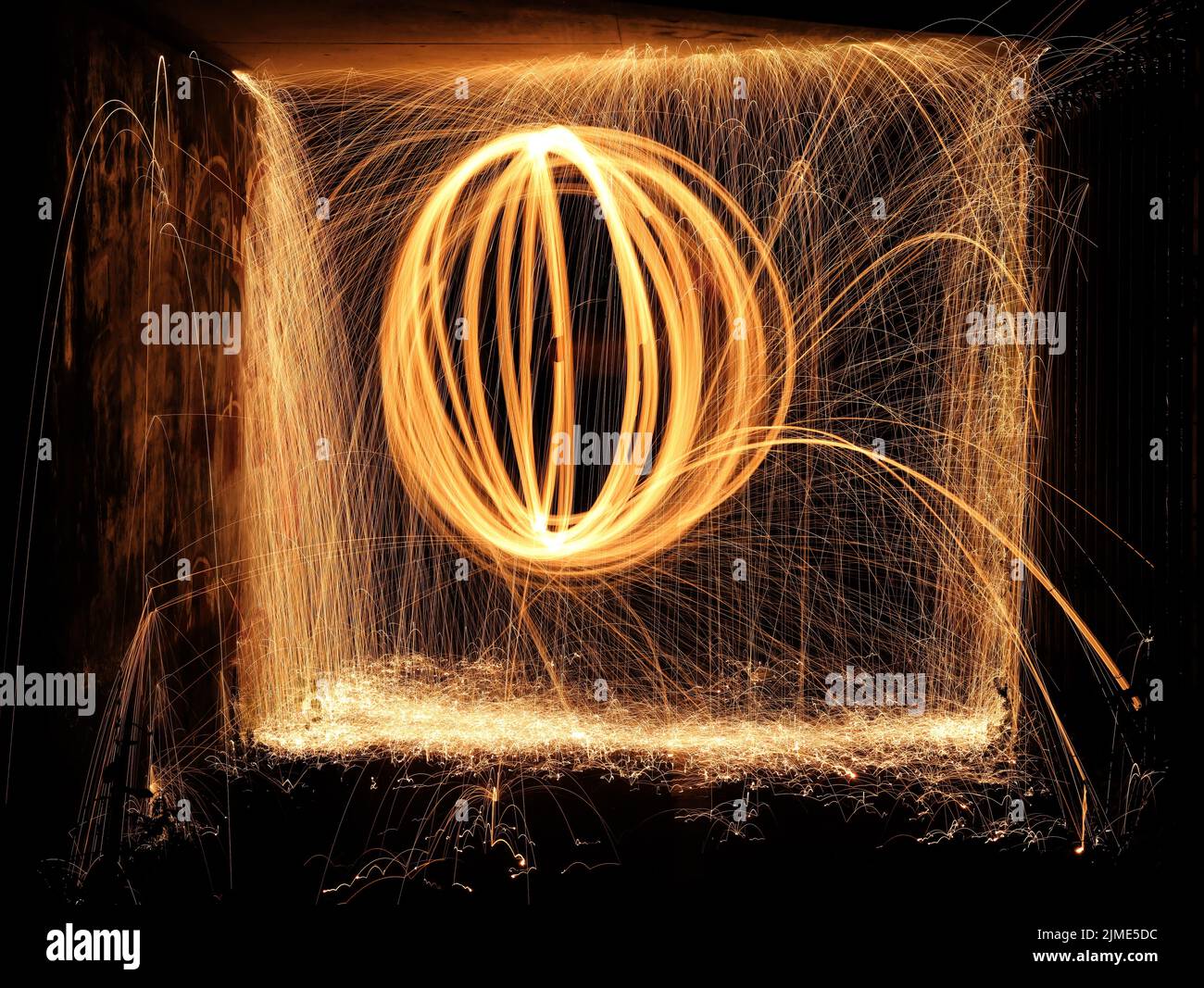 Steel wool spinning in a tunnel, throwing off yellow and orange sparks