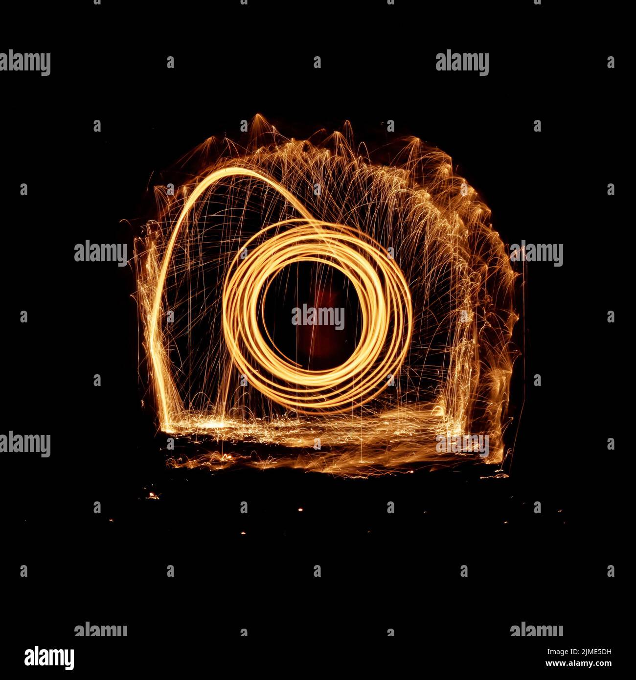Steel wool spinning in a tunnel, throwing off yellow and orange sparks