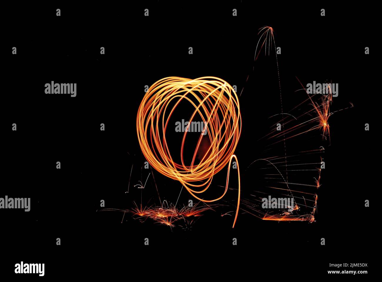 Steel wool spinning in a tunnel, throwing off yellow and orange sparks