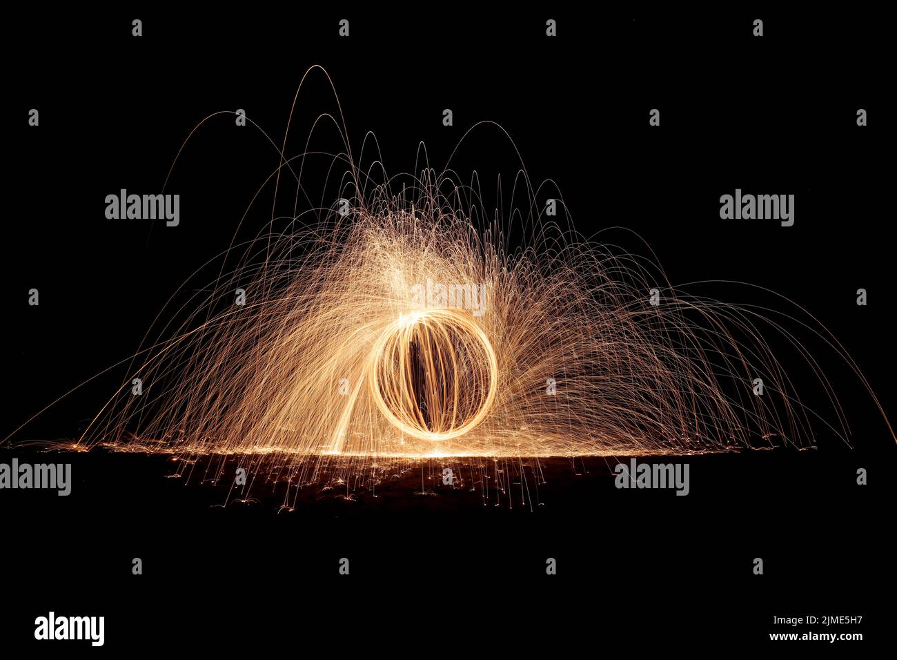 Steel wool spinning on a beach , throwing off yellow and orange sparks