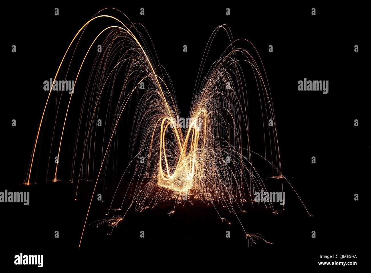 Steel wool spinning on a beach , throwing off yellow and orange sparks